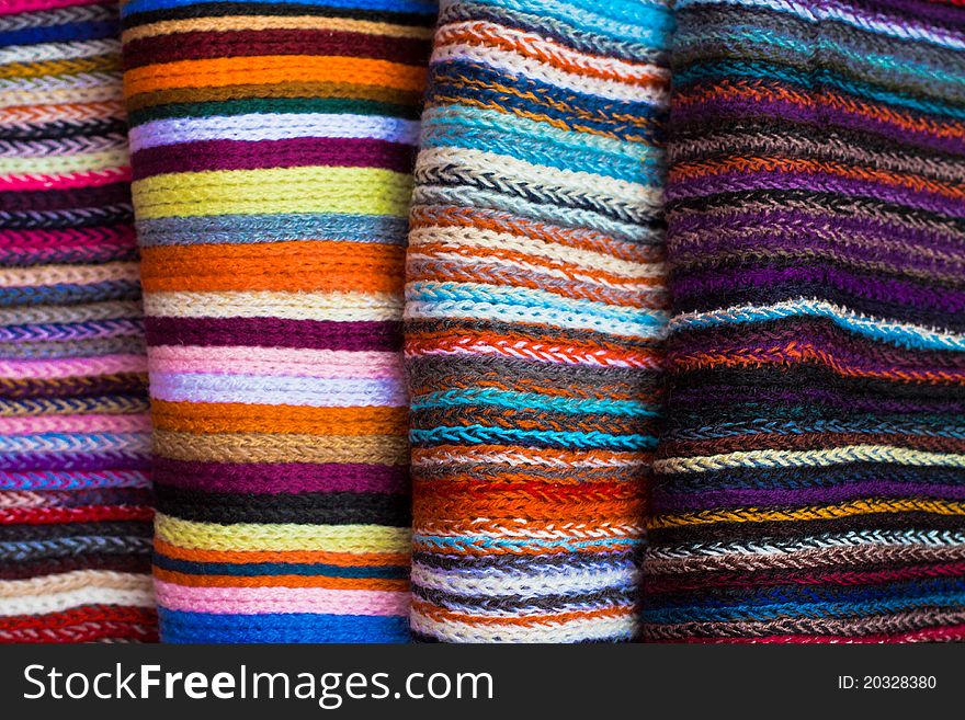 A folded pile of colorful cloth with different woven patterns