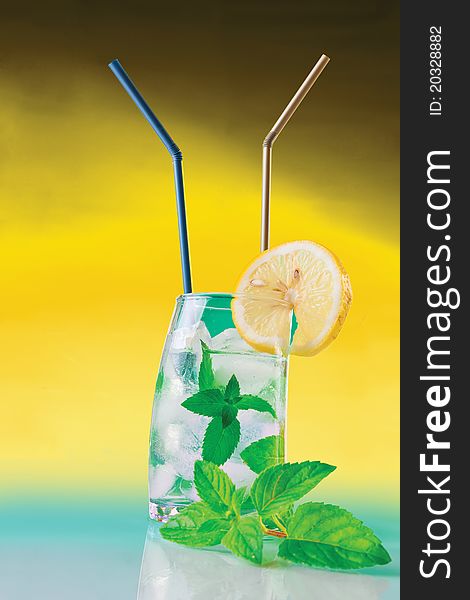 Fresh drink with mint and ice on yellow background