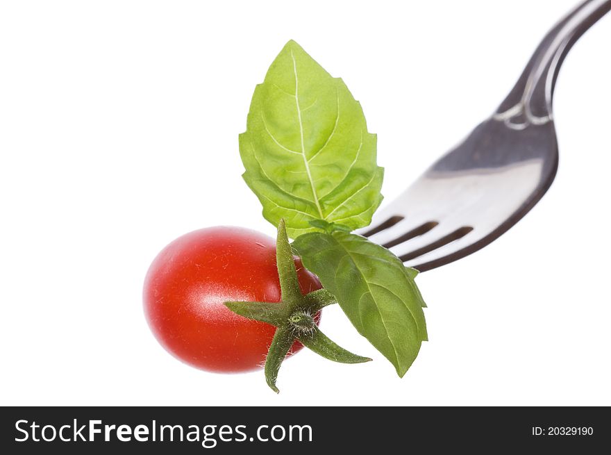 Fork with basil and tomato on white background