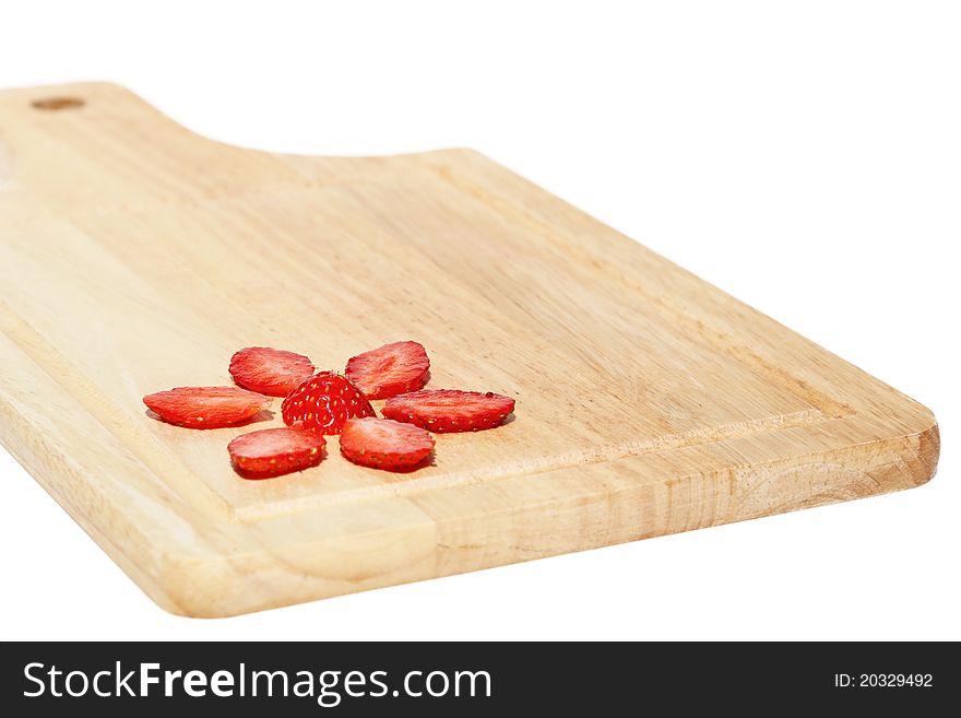 Flower, made of fresh strawberries on a kitchen hardboard on a white background