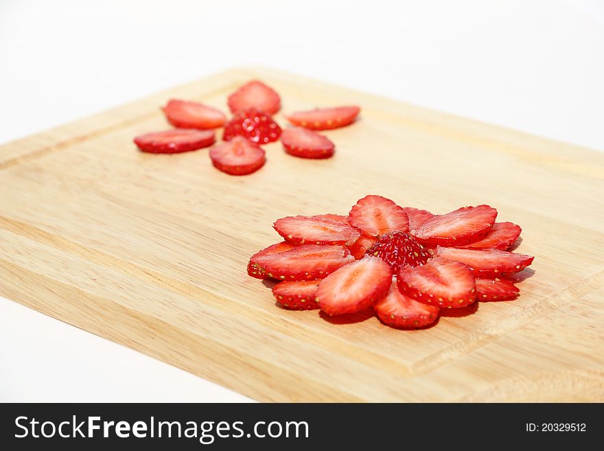 Flower, made of fresh strawberries on a kitchen hardboard