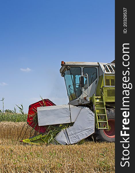 Combine harvester collecting wheat or barley from a rural field on a summers day. Combine harvester collecting wheat or barley from a rural field on a summers day