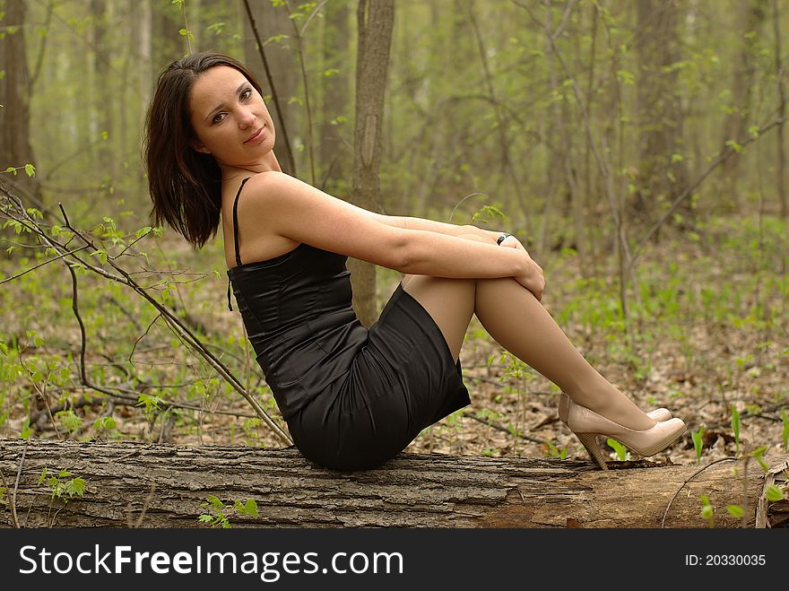 Girl sitting on a log in the spring forest. Girl sitting on a log in the spring forest