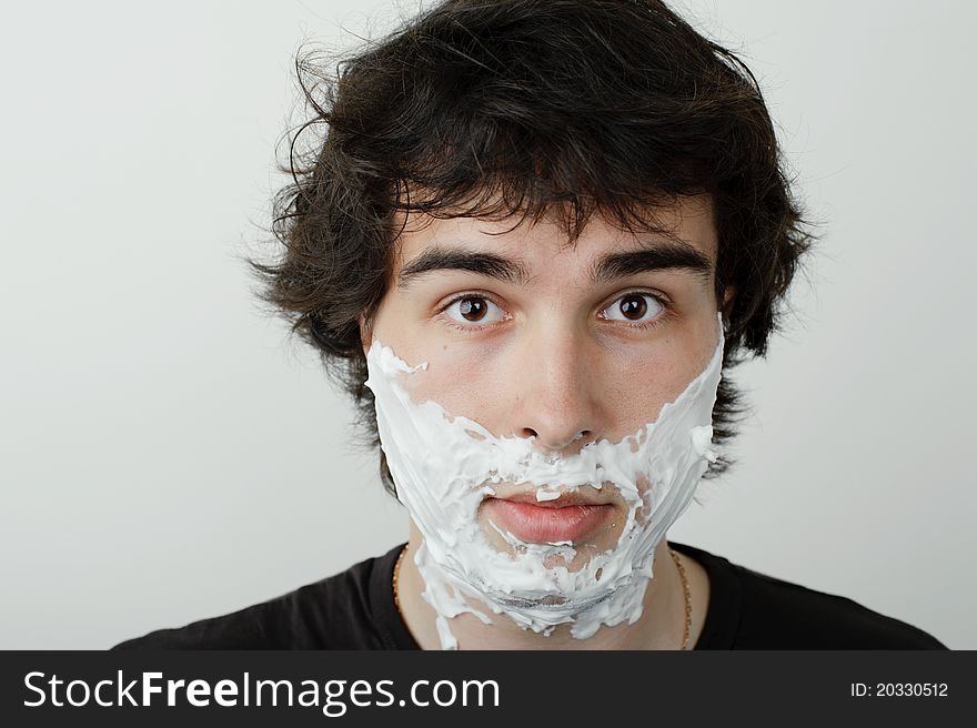 An image of a young man with shaving foam on his face