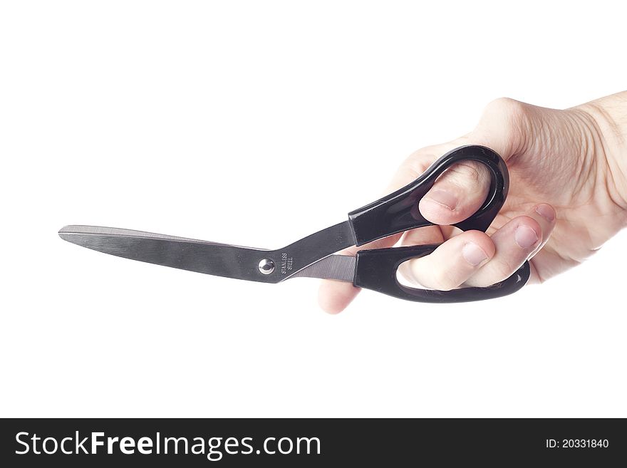 A hand holding a pair of black scissors against a white background
