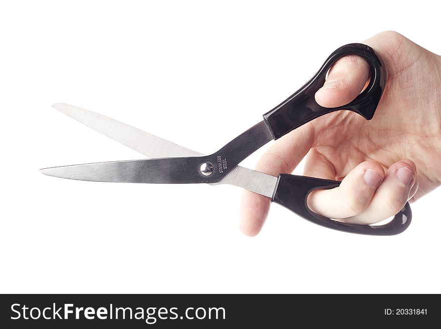 A hand holding a pair of black scissors against a white background