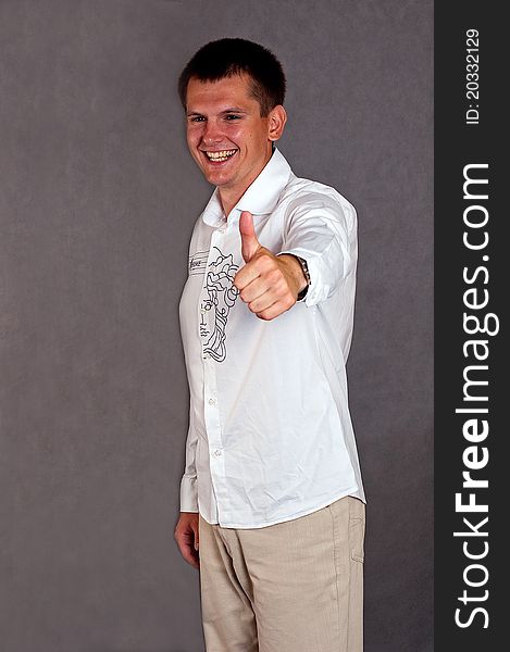 Young man on the grey background demonstrating OK sign