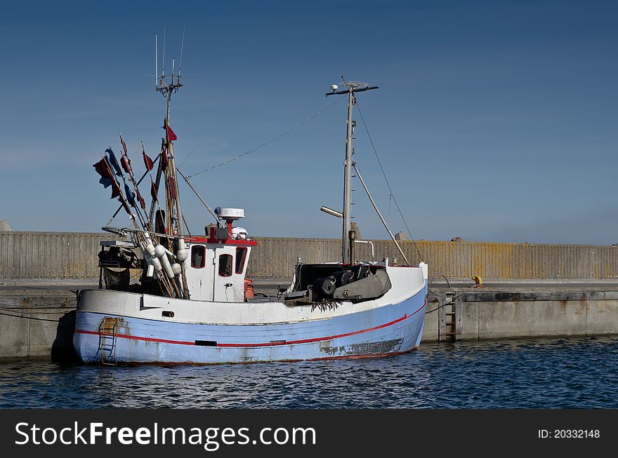 Small blue and white fishing boat laying in harbour. Commercial fishing. Small blue and white fishing boat laying in harbour. Commercial fishing.