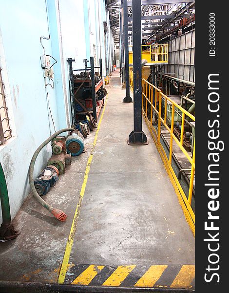 Very narrow and dirty maintained Industrial hallway with yellow hand railings and floor storage. Very narrow and dirty maintained Industrial hallway with yellow hand railings and floor storage.