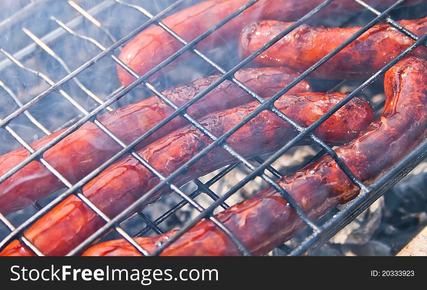 Grill sausage on barbecue grid in smoke