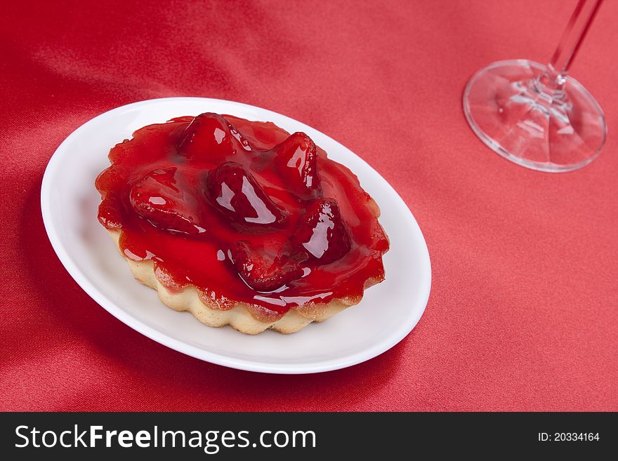Strawberry cake topped with strawberry glaze on red satin background
