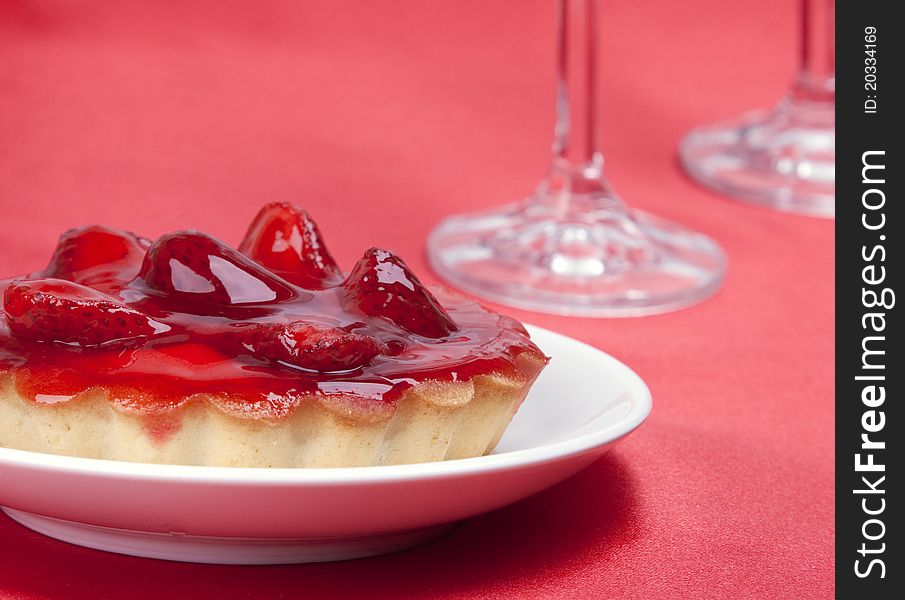 Strawberry cake topped with strawberry glaze on red satin background