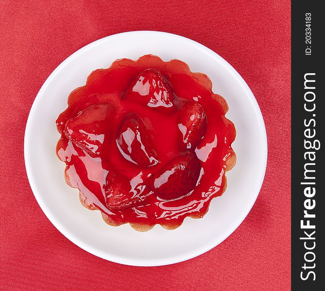 Strawberry cake topped with strawberry glaze on red satin background