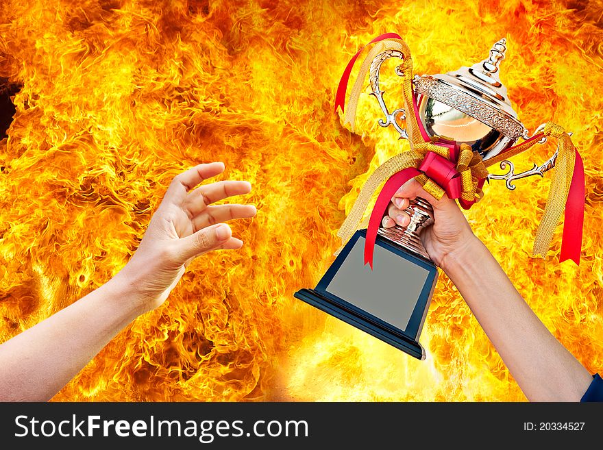 Cup with ribbon in hand on fire background. Cup with ribbon in hand on fire background