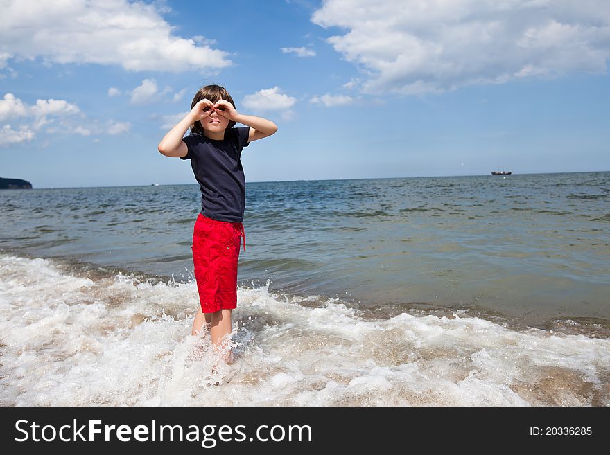 Boy standing in the sea, and pretends to hold in the hands of binoculars. Boy standing in the sea, and pretends to hold in the hands of binoculars