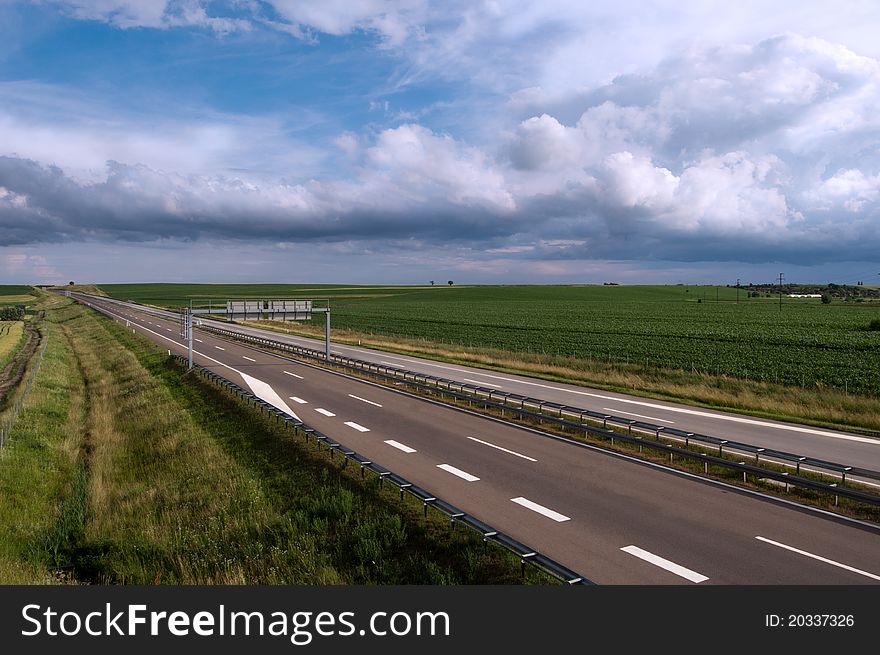 Long empty highway road under cloudy skies
