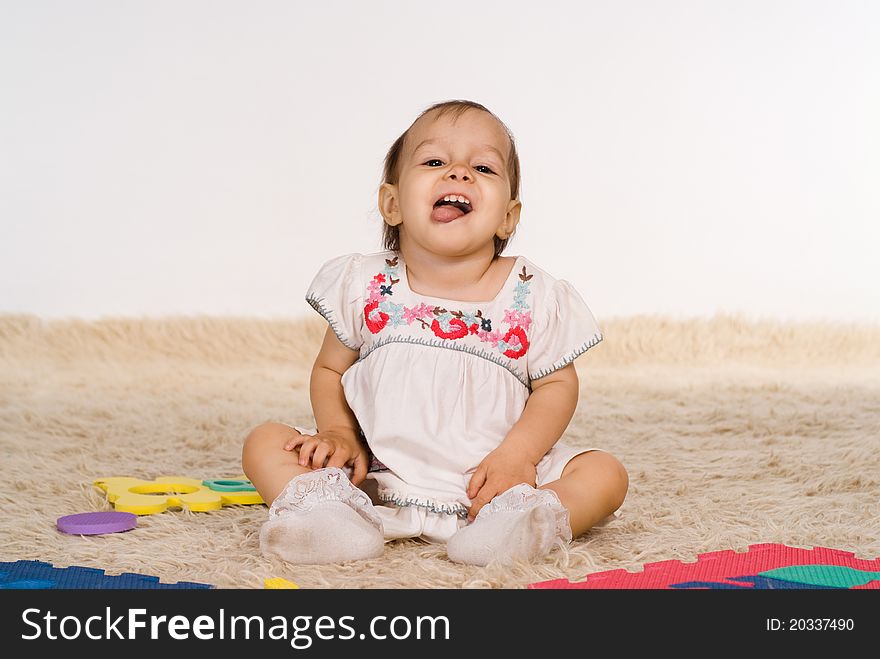 Funny little girl playing on the carpet