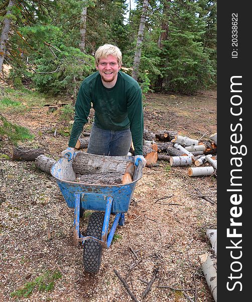 A teenage boy pushing a wheelbarrow in the forest. A teenage boy pushing a wheelbarrow in the forest