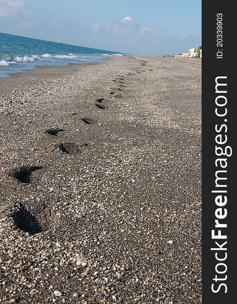 Footprints on the sand with waves crashing near