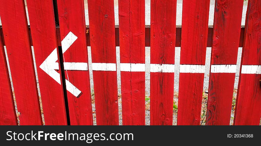Indicating arrow painted on red fence. Indicating arrow painted on red fence