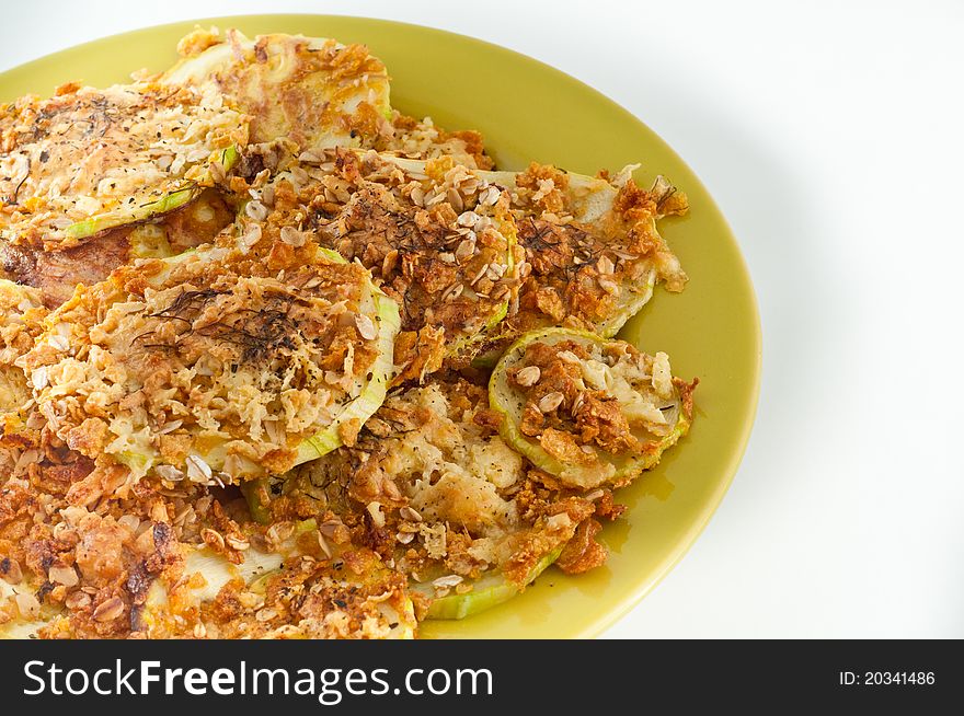 Healthy Zucchini baked in electrical oven , on a green plate isolated on a white background