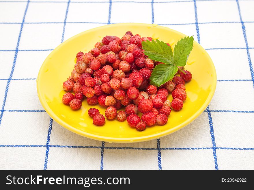 Strawberries on a yellow plate with green leaf