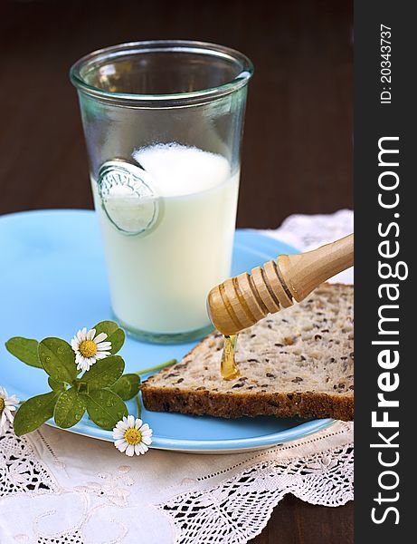 Healthy breakfast - glass of milk, multigrain toast and golden honey running from wooden drizzler. Healthy breakfast - glass of milk, multigrain toast and golden honey running from wooden drizzler