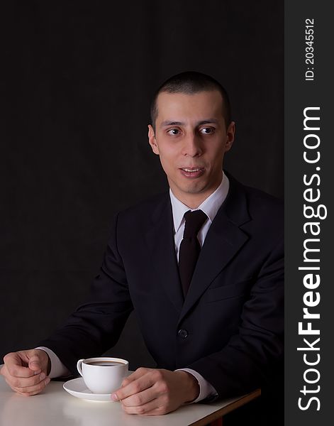 Businessman drinking coffee isolated on black