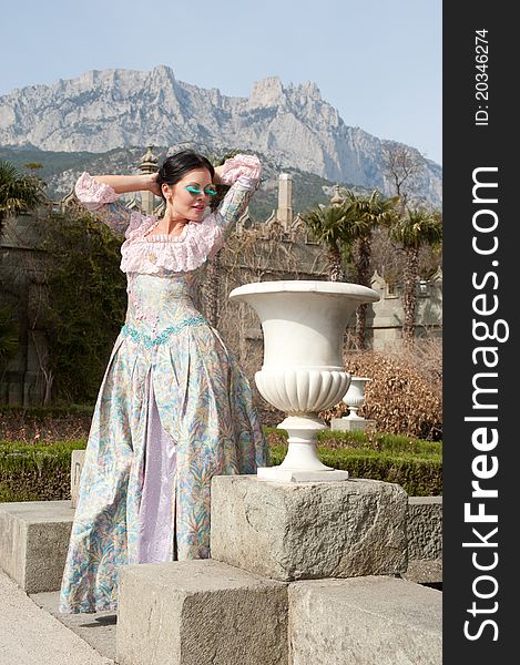 Woman in classical dress standing on the stairs near the castle