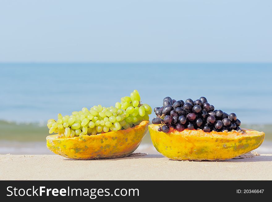 Tropical papaya and grape on the sandy shore. Tropical papaya and grape on the sandy shore