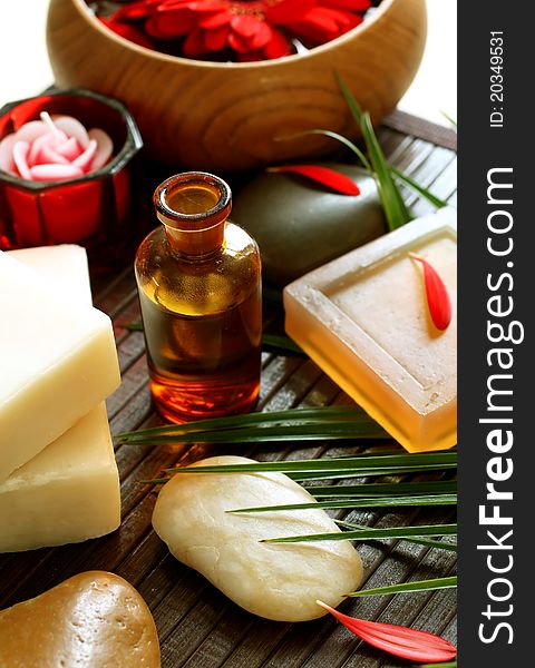 Spa composition of bottle, soap, stones and red flowers