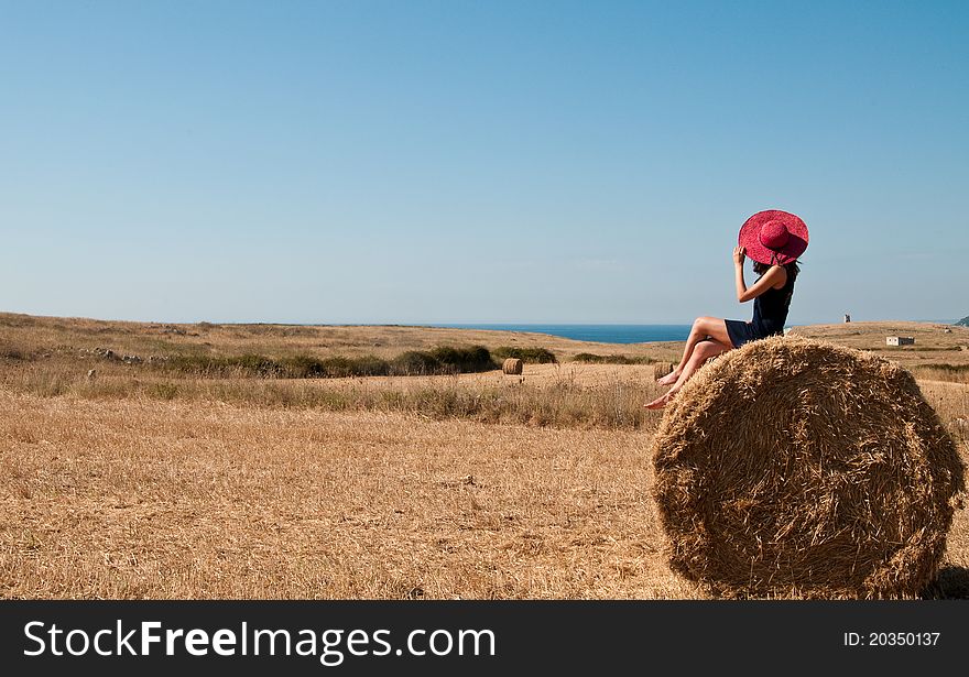 Girl with a pink hat on a haystack. Girl with a pink hat on a haystack