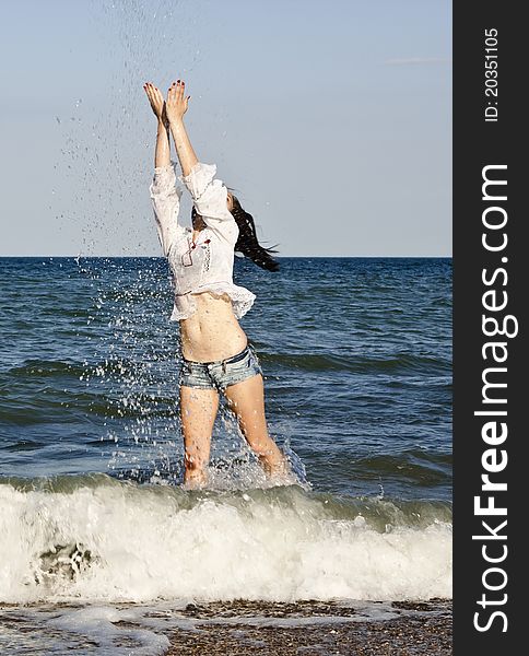 Girl in denim shorts and a t-shirt walks on the beach. Girl in denim shorts and a t-shirt walks on the beach