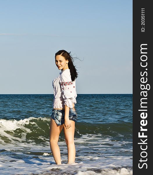 Girl in denim shorts and a t-shirt walks on the beach. Girl in denim shorts and a t-shirt walks on the beach