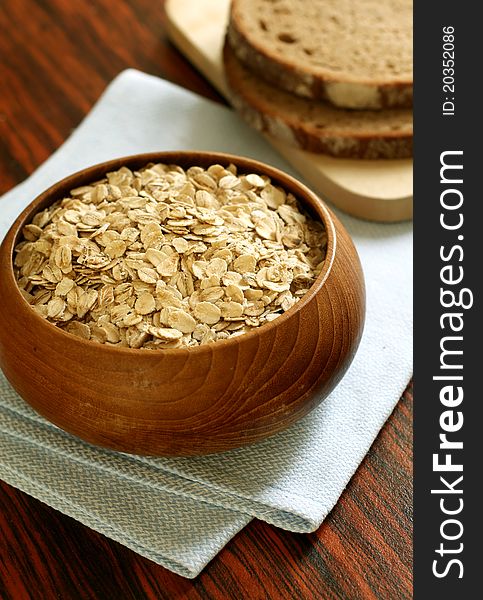 Oats in wooden bowl and bread on table - food ingredient