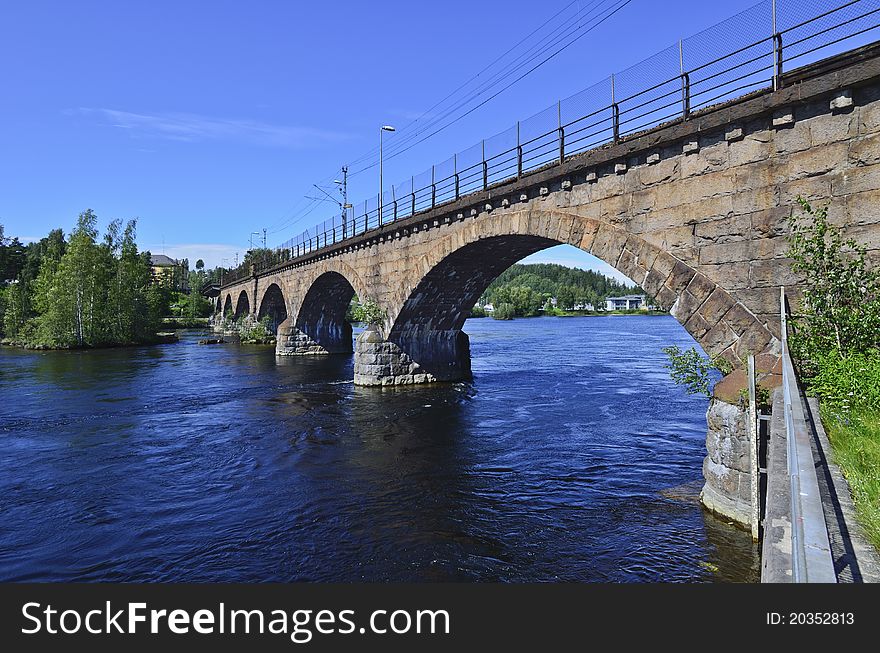 The old railway bridge crosses the beautifully blue Begna River just a hundred yards above the Hoenefoss Falls.