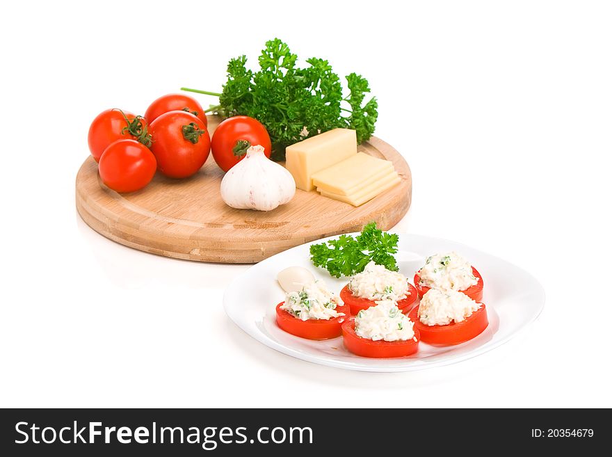 Sliced tomato with cheese and garlic sauce on a plate. Ingedients on a board. Sliced tomato with cheese and garlic sauce on a plate. Ingedients on a board.