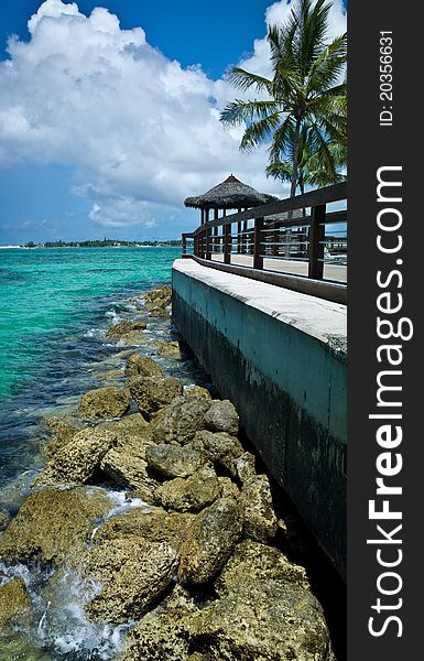 Beach hut overlooking rocks, a bulkhead, and caribbean island lagoon. Beach hut overlooking rocks, a bulkhead, and caribbean island lagoon