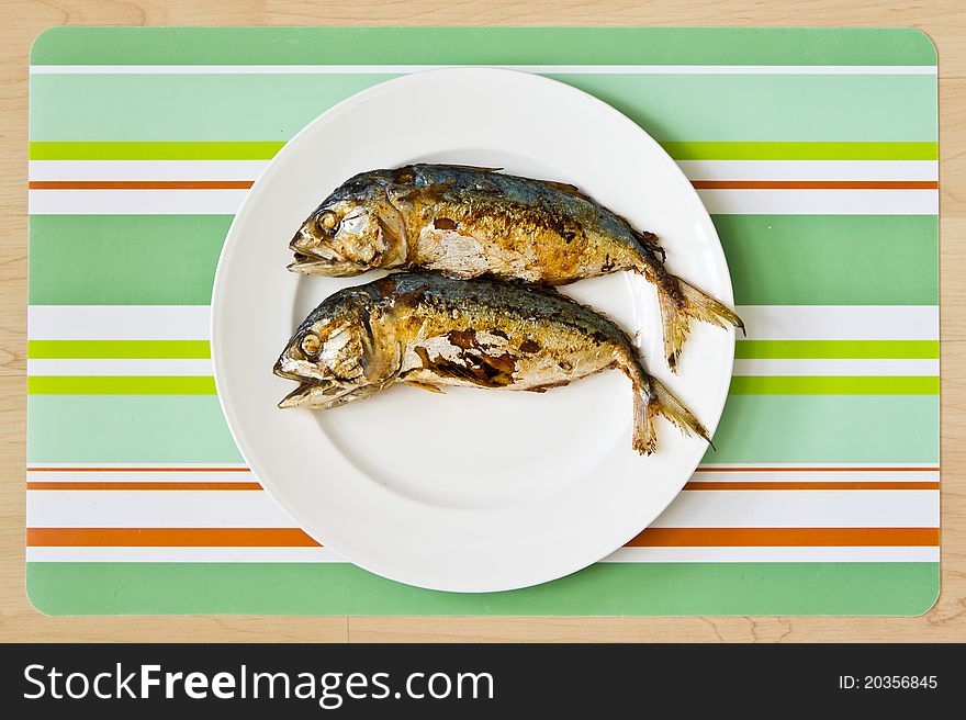 Two fried mackerel fishs on white plate