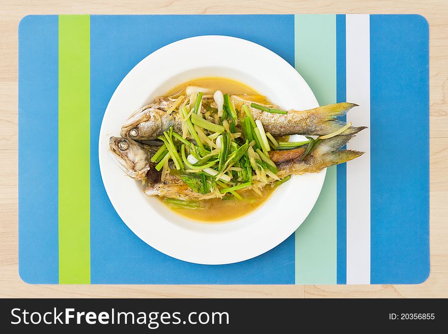 Two steamed mackerel fishes with ginger on white plate
