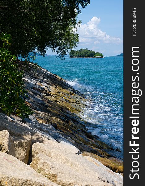 Waves crashing against a rocky shore with an island in the background