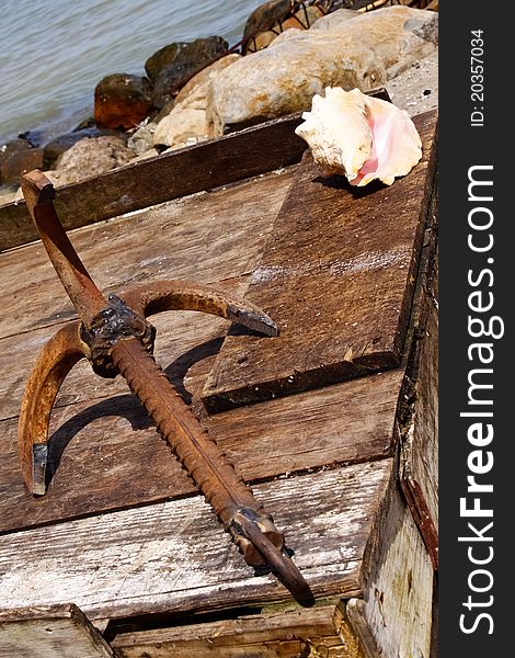 A detail shot of a rusty anchor and beautiful conch shell near the piet in the fishing village of Anse La Raye on the beautiful Caribbean island of St. Lucia. A detail shot of a rusty anchor and beautiful conch shell near the piet in the fishing village of Anse La Raye on the beautiful Caribbean island of St. Lucia.