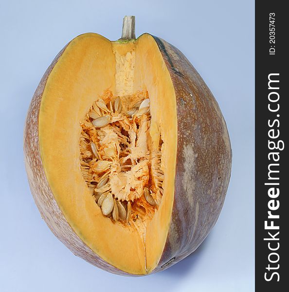 This is a mature pumpkin, was on a blue background, cutting a piece of, revealing the many seeds