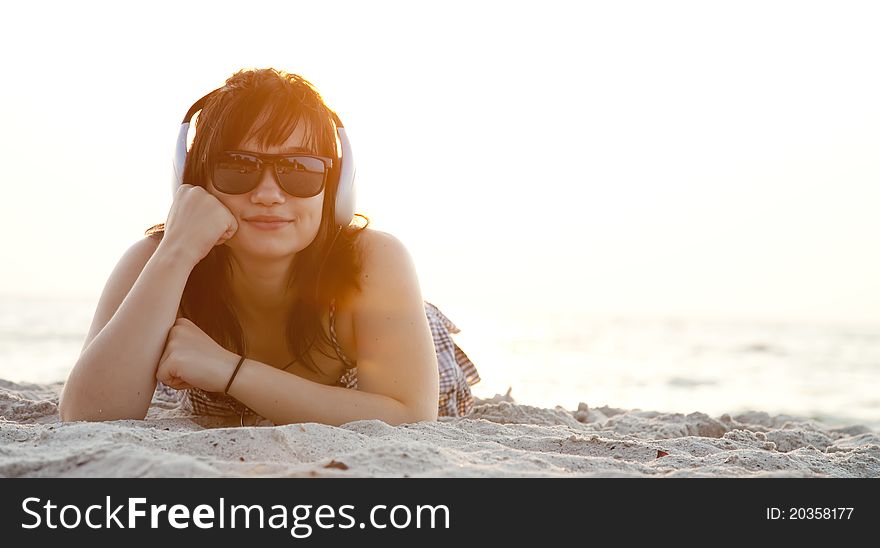 Beautiful brunette girl with headphones at beach sand.