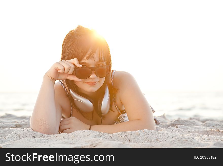 Beautiful brunette girl with headphones at beach sand.