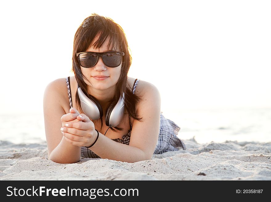 Beautiful brunette girl with headphones at beach sand.