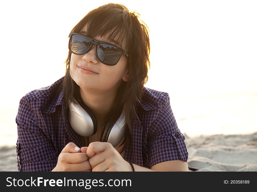 Beautiful brunette girl with headphones at beach sand.