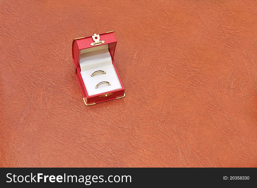 Two golden wedding rings in a fancy red box isolated on leather