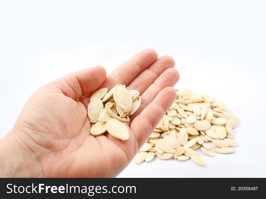 Pumpkin seeds in hand on white background