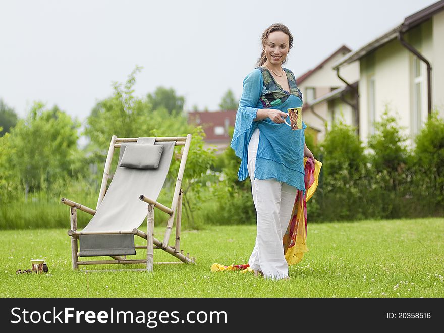 Cute woman with cup near a deck chair. Cute woman with cup near a deck chair